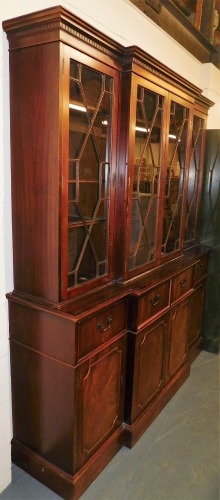 A 20thC mahogany breakfront display cabinet, the top with a moulded dental cornice, above four astragal glazed doors enclosing an arrangement of shelves, the base with four drawers and four cabinets, on a plinth base, 197cm high, 164cm wide, 55cm deep.