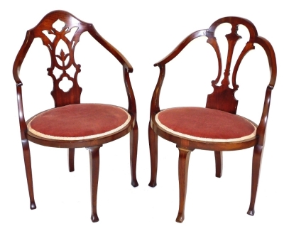 A pair of Edwardian mahogany armchairs, each with carved splats, oval red draylon seats, raised on cabriole legs.