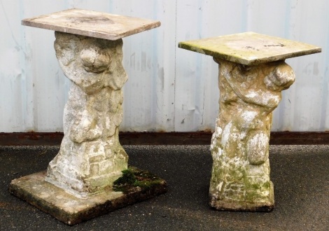 Two composition garden plinths, each with a square top supported by a carved column depicting a boy holding a basket of fruit, each approximately 63cm high.