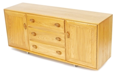 An Ercol light elm sideboard, with three central drawers flanked by cupboard doors, raised on castors, 68cm high, 156cm wide, 43cm deep.