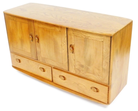 An Ercol light elm sideboard, the oblong top over three doors, over a pair of frieze drawers, on castors, 76cm high, 129cm wide, 49.5cm deep.