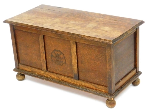 An early 20thC oak blanket chest, the front carved with a leaf pattern, raised on ball feet, 50.5cm high, 91cm wide, 37cm deep.