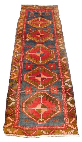 A Kilim blue ground runner, decorated with five central medallions and floral motifs within a repeating leaf border, 290cm x 100cm.