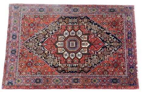 A Persian Gholtogh red ground rug, decorated with a central radiating medallion, decorated with animals and trees, flowers to the ground, within a repeating floral border, 150cm x 97cm.