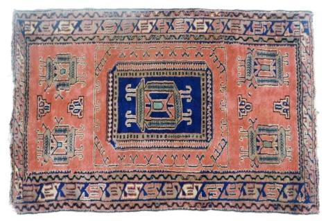 A Turkish red ground rug, decorated with five framed floral motifs, within repeating geometric borders, 15c5m x 103cm.