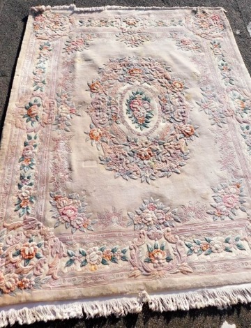 A Chinese beige ground rug, decorated with a central oval medallion of roses and laurel wreath, within floral borders, 301cm x 244cm.