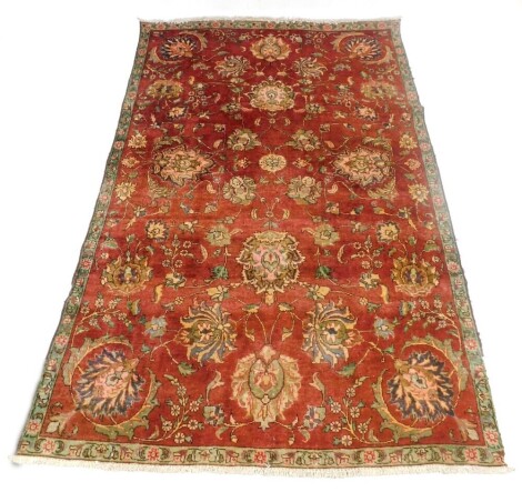 A Sarouk red ground rug, decorated with bold floral motifs, within a repeating floral border, 277cm x 177cm.