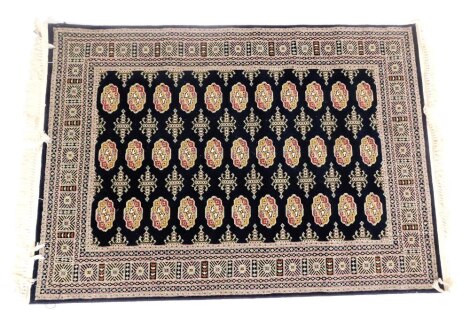 A Bokhara black ground rug, decorated with three rows of ten guls, within repeating geometric borders, 170cm x 118cm.