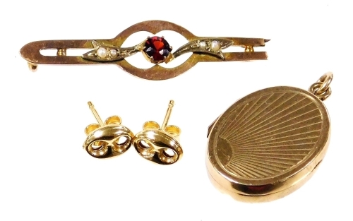 A pair of 18ct gold oval earrings, 1.2g, a 9ct gold oval photo locket with sun burst engraving, 3.5g, and an Edwardian garnet and seed pearl bar brooch, stamped 9ct, 1.2g. (3)