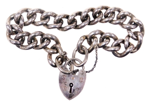 A heavy silver curb link bracelet, on a heart shaped padlock clasp, with safety chain as fitted, 57.5g.