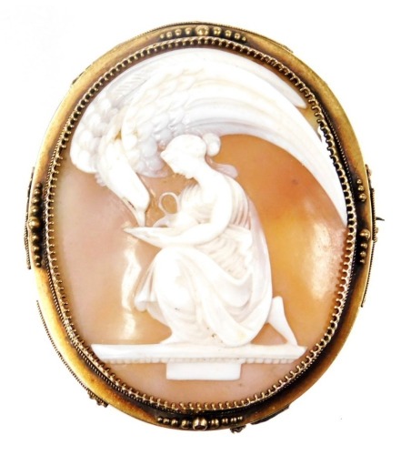 A late 19thC shell cameo brooch, Zeus as an eagle, drinking from a cup held by Hebe, in a yellow metal oval mount, with safety pin as fitted.