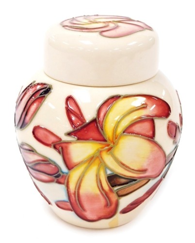 A Moorcroft Frangipani pattern pottery jar and cover, printed marks and signed to underside, 11cm high, boxed.