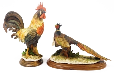 Two Capodimonte figures, one of a cockerel, raised on a wooden base, the other of a pheasant raised on a wooden base, monogrammed GA.