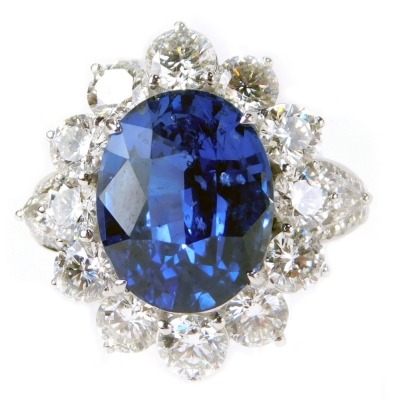 7000 N/B - An 18ct white gold sapphire and diamond cluster ring, with oval cut blue sapphire, totaling 7.05ct, surrounded by a halo of round brilliant cut diamonds, approx 2.44ct, with pear cut and brilliant cut diamond shoulders, each approx 0.32ct and 0