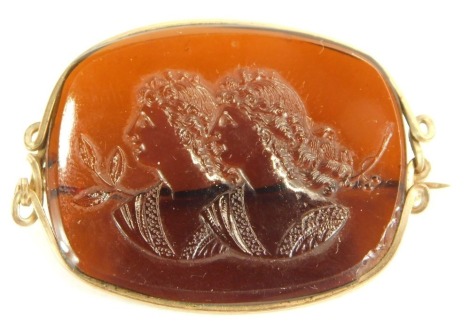 A late 19thC brooch, of oval form, with central amber stone depicting two maiden heads, in a gold coloured wire work frame, with single pin back, 4cm wide, 8.2g all in.