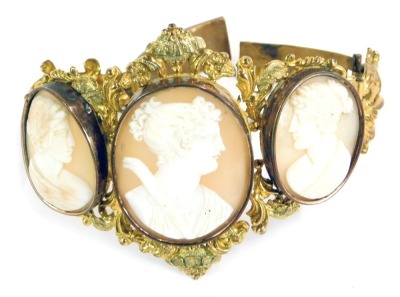 A late 19thC/early 20thC shell cameo bracelet, formed with three oval cameos depicting maidens in flowing headdress, in a gilt bangle frame, with heavy scroll detail, the front section 8cm wide, 6cm high, 37.1g all in.