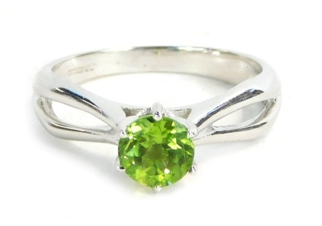 A 9ct white gold dress ring, set with round brilliant cut peridot in claw setting with twist design shoulders, ring size N½, 3.6g all in, boxed.