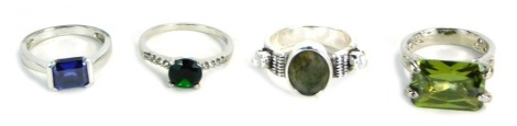 Four dress rings, comprising a CZ M&S green stone ring, a silver blue CZ set dress ring, a costume jewellery rough stone set ring and a green rectangular set paste stone set, boxed. (4)