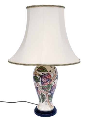 A Moorcroft table lamp, on a cream ground with pink and purple flowers, on ebonised base, with cream shade, 54cm high.