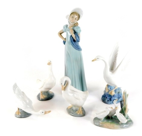 A group of Spanish porcelain figures, comprising geese, and standing lady wearing a bonnet, each with applied green baize covered bases, possibly Nao. (6)