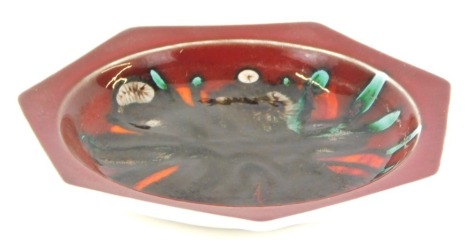 A Poole pottery hexagonal plate, on a red ground, 15cm diameter.