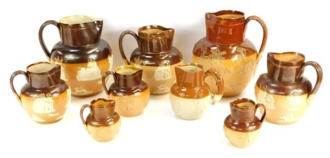 A group of Doulton Lambeth and other stoneware two tone harvest jugs, each with relief moulded figural decoration, the largest 21cm high, the smallest 8cm high.