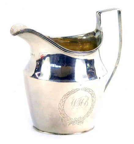 A George III silver cream jug, with a shaped and fluted handle, with Neo Classical wreath, bearing initials W M B, maker's mark indistinct, London 1803, 2¾oz.