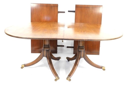 A mahogany twin pedestal dining table in the Regency style, with parquetry banding on out splayed legs, 73cm high, 160cm wide, 104cm deep, with two additional leaves.