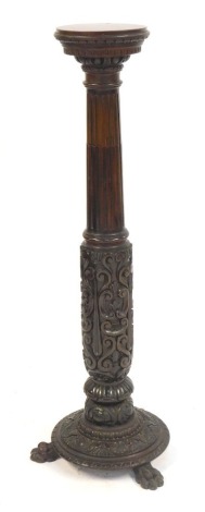 A mahogany plant stand, on circular carved and reeded column, with paw feet, 106cm high, 22cm diameter.