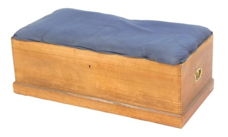 A pine blanket box or stool, with a blue upholstered cushion seat, on box lid, on a plinth, terminating in castors, 33cm high, 92cm wide, 46cm deep. The upholstery in this lot does not comply with the 1988 (Fire & Fire Furnishing) Regulations, unless sold