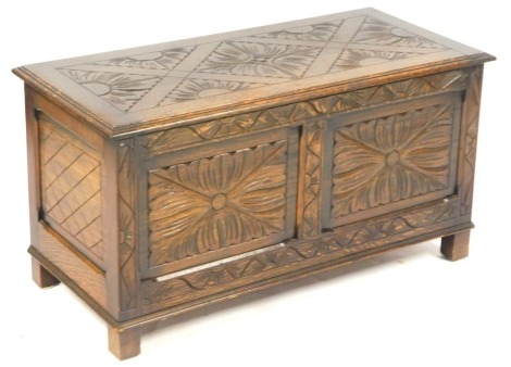 An oak blanket box, the carved lid, above arrangement of two carved sunflower panels, on stiles, 48cm high, 91cm wide, 43cm deep.