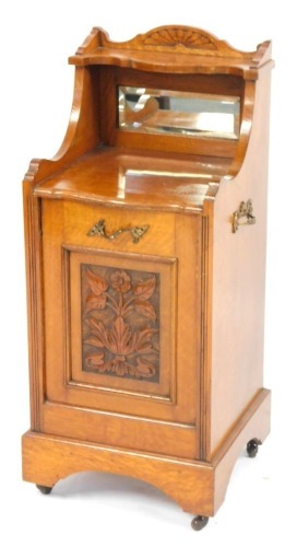 An Edwardian oak coal purdonium, with a raised cornice, with mirrored back, with pull out carved drawer with brass handles, terminating in castors, 85cm high, 36cm wide, 34cm deep.