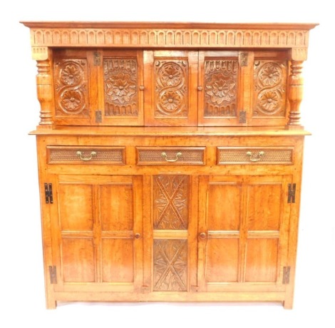 An oak court cupboard, in the 17thC style, carved overall with roundels, leaves and scrolls with unusual carved drawers, on stiles, 182cm high, 166cm wide.