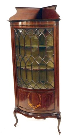 An Edwardian mahogany corner display cabinet, with a moulded cornice on concave mahogany inlaid astragal glazed door, with cupboard base on out splayed legs, 184cm high, 52cm deep, 79cm diameter.