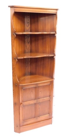 An Ercol light elm corner cabinet, with three tiered shelf section above single door, 183cm high, 70cm wide, 45cm deep.