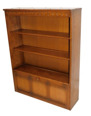 An Ercol light elm bookcase, with four shelf rack with two cupboard base, on stiles, 126cm high, 98cm wide, 30cm deep.