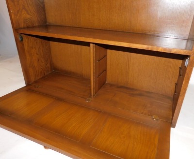 An Ercol light elm bookcase, with four shelf rack with two cupboard base, on stiles, 126cm high, 98cm wide, 30cm deep. - 2