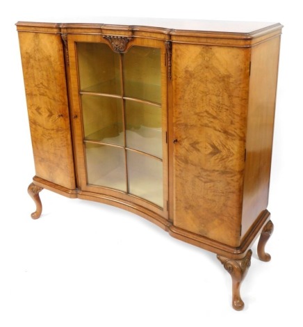 A 20thC walnut concave display cabinet, with central section with six rectangular panel glazed door, with two enclosed cupboards, on out splayed cabriole legs, 116cm high, 126cm wide, 42cm deep.