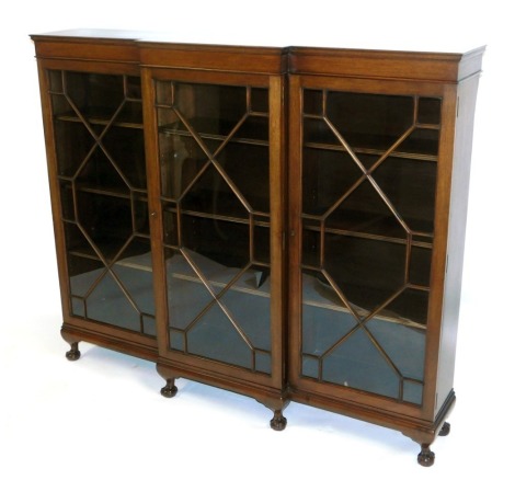 A 20thC mahogany breakfront bookcase, with three glazed panel doors, on bracket feet, 132cm high, 156cm wide, 32cm deep.