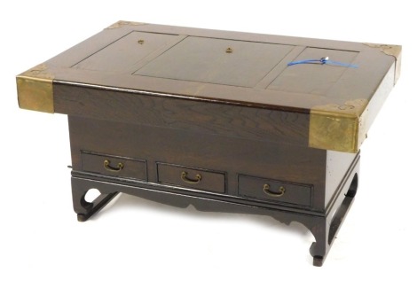 An Eastern mahogany coffee table, with brass corners, the top with three lidded compartment, each with copper liner, 45cm high, 88cm wide, 57cm deep.