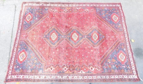 An Afghan red ground rug, with medallion and floral border, with tassel ends, 313cm x 224cm.