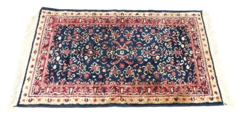 A silk prayer rug, on a red and cream floral ground, with white tassel ends, 108cm x 64cm.