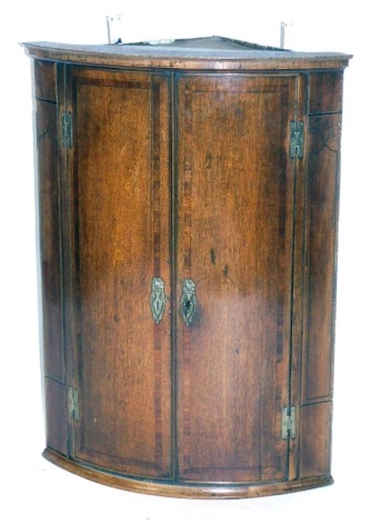 A 19thC oak bowfront corner cabinet, with a moulded top, with two cupboard doors, with brass spandrels, 96cm high.