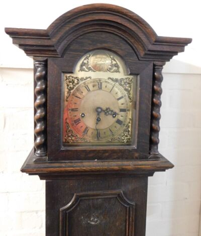 An early 20thC oak grandmother clock, the brass break arch dial with floral and foliate spandrels, chapter ring bearing Roman numerals, eight day movement with Westminster chimes, the arched hood raised on spiral twist columns, plain trunk raised on a pli