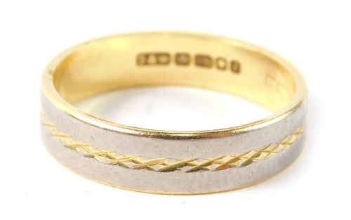 An 18ct gold bi-colour wedding band, with a border on white gold, with cross hatched hammered centre, on a yellow metal band, size N, 3.8g all in.