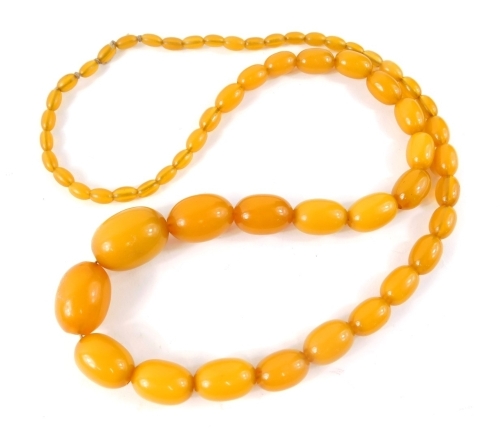 A butterscotch amber necklace, of graduated form on string strand, with the largest bead 3cm wide, the smallest, 8mm wide, 76g all in.