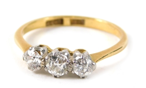 An 18ct gold three stone diamond dress ring, set with three old cut diamonds, each in claw setting, the central stone approx 0.15ct, flanked by two smaller stones, each approx 0.08ct, in a raised white gold basket setting, on a yellow metal band, ring siz