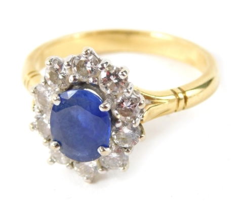 A sapphire and diamond cluster ring, with central oval sapphire in four claw setting, surrounded by ten round brilliant cut diamonds, each approx. 0.10ct, totalling approx 1ct, with V splayed shoulders, on a plain yellow metal band, ring size N½, yellow m