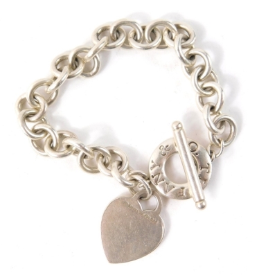 A charm bracelet, with curb linked charms, a heart shaped pendant, on single bar white metal stamped 925, 43.2g all in, in Tiffany and Co box.