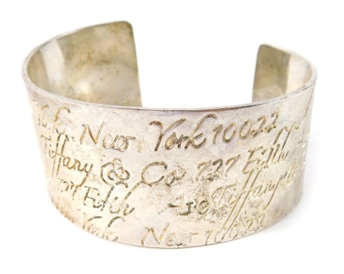 A silver bangle, inscribed New York, number 1002, stamped 1997, 7cm wide, 53g all in, in Tiffany and Co. box.